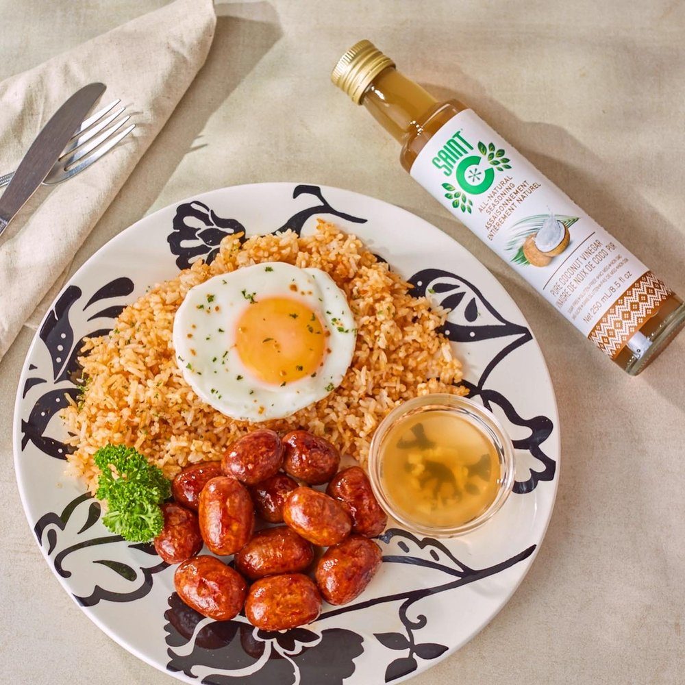 Saint C Pure Coconut Vinegar beside a plate of garlic rice, egg and longganisa with a vinegar dip